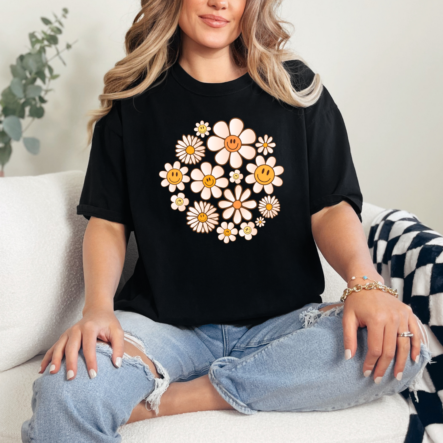 A person wearing a black graphic t-shirt with a design of daisies in a circular pattern.